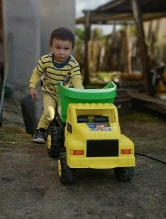 Mathi de niño empujando un camión de juguete en el patio